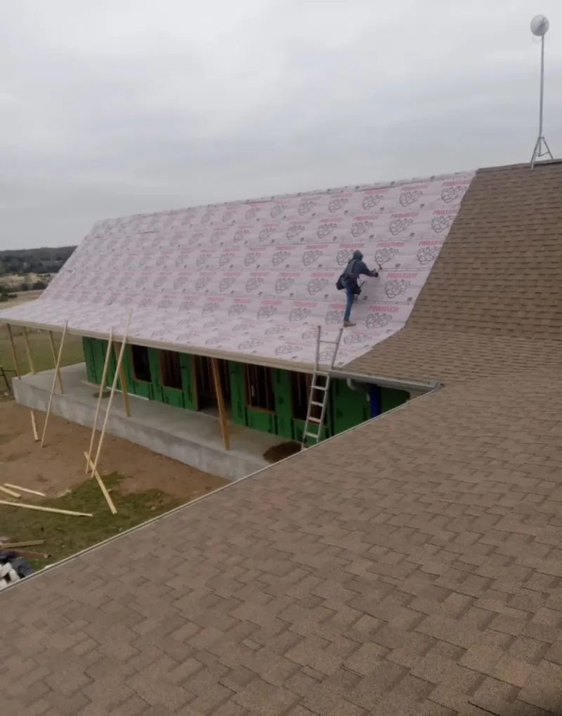 Worker preparing underlayment for a metal roof installation in North Bergen